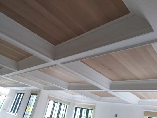 Coffered wood ceiling installation showing multiple framed wood panel sections.